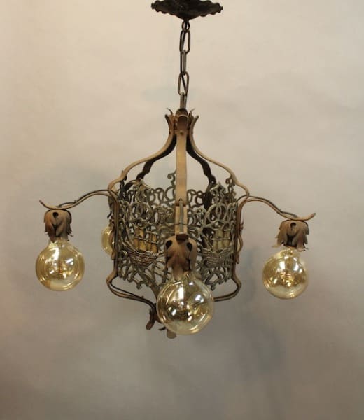 15976. Spanish Revival Chandelier With Filigree With Ship Motif with intricate metalwork and four hanging glass globes emitting a warm light.