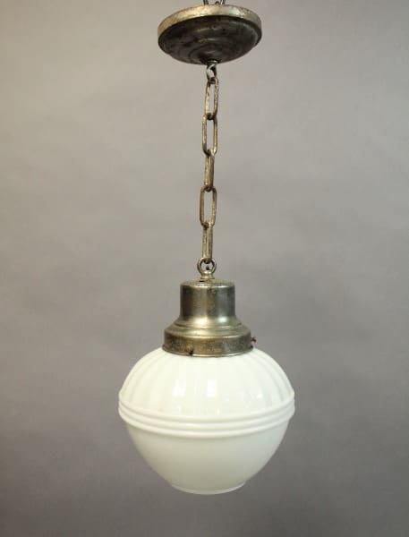 16044 pendant light with brass fittings and a white glass globe, hanging from a chain against a gray background.