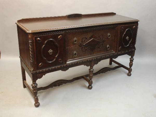 16146. Carved Walnut Sideboard Circa 1920's with brass hardware, featuring two cabinets and a central drawer, supported on turned legs.