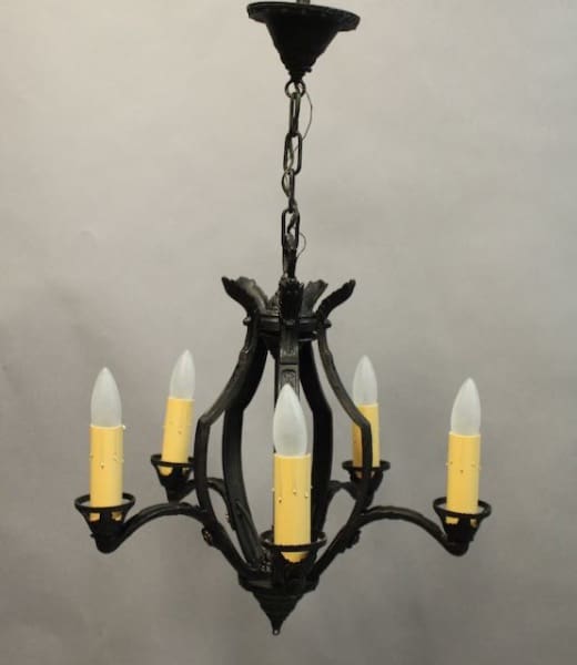 A black 16186. Circa 1920's Five Light Chandelier with five arms, each holding a white, candle-shaped light bulb, hangs from a chain against a gray background.