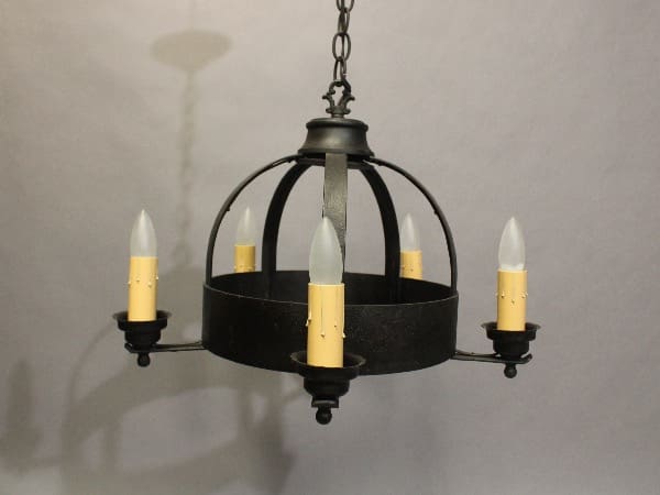 A 16299. 1920's Spanish Revival chandelier with five candle-style lights hanging from a chain, against a gray background.