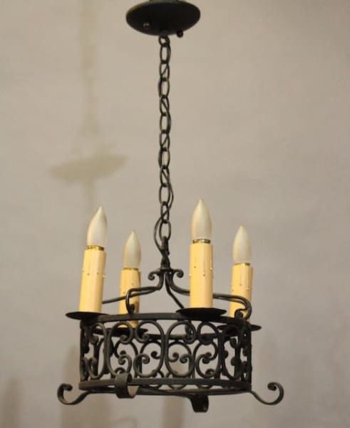 16417. 1920's Wrought Iron Chandelier with five candle-like bulbs hanging from a chain, set against a plain, light-colored wall.