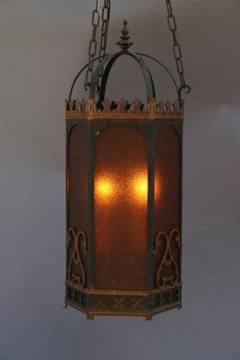 An ornate 1679. Large Pendant With Amber Glass emitting a soft light through its patterned, rust-colored panels.