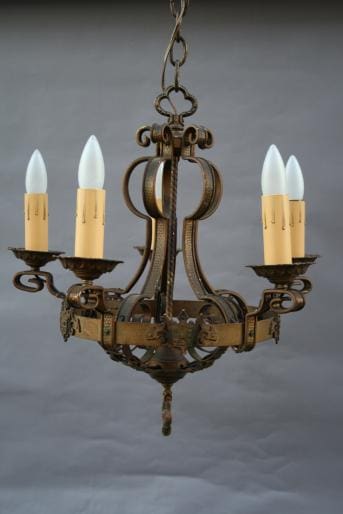 An 2005. Original Spanish Revival Chandelier with five arms and candle-like bulbs, suspended by a chain, set against a plain gray background.