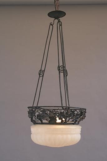 An ornate hanging light fixture with a frosted glass bowl suspended by decorative metal chains, illuminated from within — the 3823. Wrought Iron Deco Chandelier.