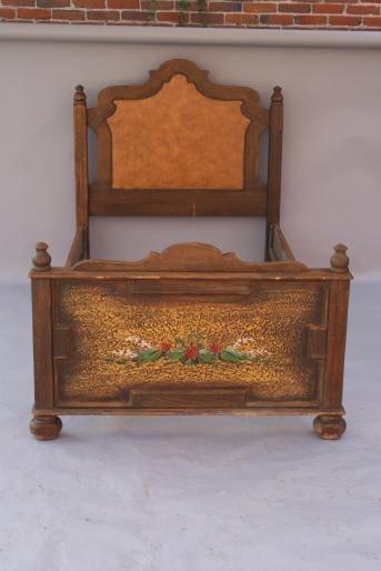 Antique wooden chair with an intricately carved backrest and 3949. Karpen De Anza Hotel Twin Bed featuring a colorful floral design, set against a brick wall.