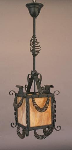 4748. Wrought iron lantern with spiral details and amber glass panels hanging from the ceiling.