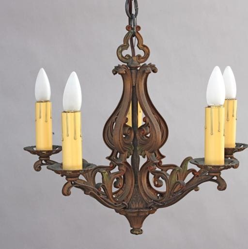 5669. Spanish Revival Polychrome chandelier with ornate scrollwork and four candle-shaped bulbs, hanging against a gray background.