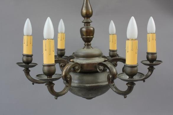 6518. Colonial Style Chandelier with six white candle-shaped bulbs on a vintage bronze fixture, set against a neutral gray background.
