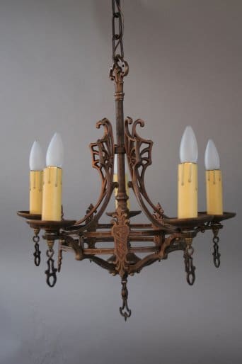 7256. Spanish Revival Chandelier With Crest Motif with ornate details, featuring five candle-shaped light bulbs against a gray background.