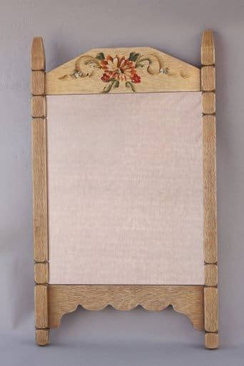 Vintage wooden paper towel holder with a decorative floral design carved at the top, mounted on a gray wall.