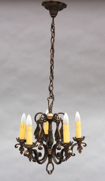 A 9252. 1920's Cast Bronze Chandelier with five candle-like lights and ornate metalwork, suspended from a chain against a neutral background.