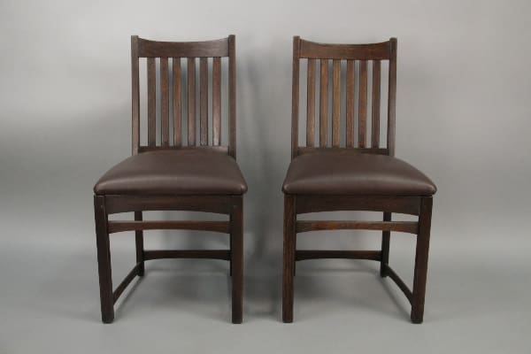 Two 10212. pairs of Arts & Crafts Oak Chairs with Soft, Curved Lines with brown upholstered seats and vertical slat backs, placed against a neutral gray background.