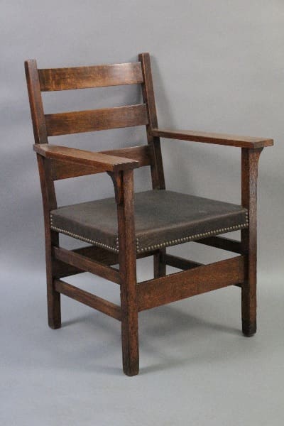 An antique 10272. Arts And Crafts Quarter Sawn Oak Armchair with leather upholstery and decorative nailhead trim, set against a neutral gray background.