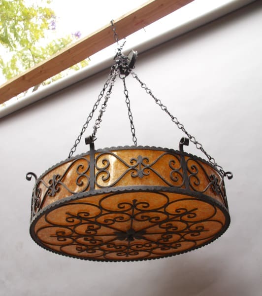 Ornate wrought iron chandelier with amber glass shade.