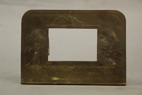 Antique brass picture frame featuring embossed oak tree designs on each side, displayed on a gray backdrop.
