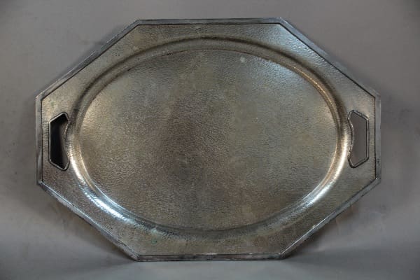 An octagonal Homan Silver Plate Hammered Charger with built-in handles, featuring a worn, textured surface.