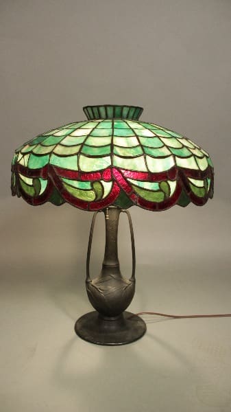 A 12106. Circa 1910 table lamp featuring beautiful original leaded glass shades with green and pink hues, set on a decorative bronze base.