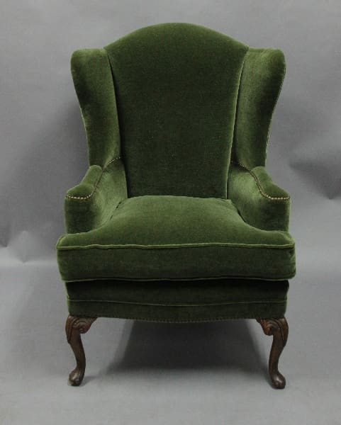 Green upholstered armchair with wooden legs.