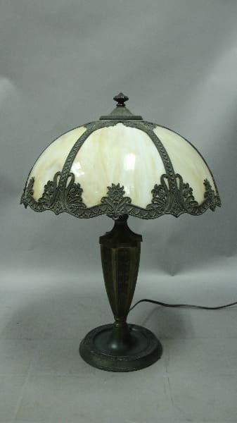 Vintage 12601. 1920's Table Lamp With Bell Shaped Slag Glass Shade with a curved white glass shade and ornate metal base on a gray background.