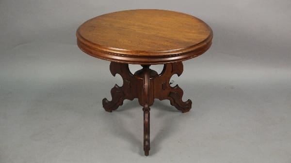 An antique 13451. Turn Of The Century Table With Tripod Base with ornate carved legs on a gray background.