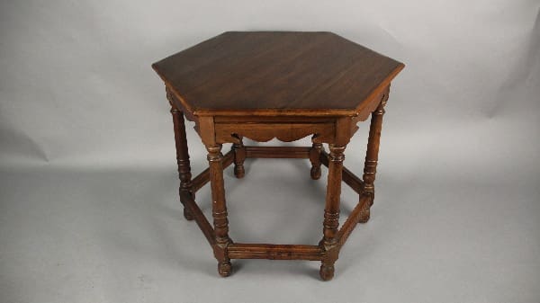 13628. 1920's Walnut Hexagonal Table with ornate legs and connected lower shelf, set against a plain gray backdrop.