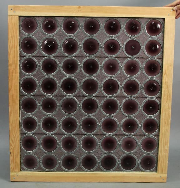 A 13692. 1920's Stained Glass Bottle Glass Panel frame holding an array of black spherical speakers arranged in a grid against a grey background.