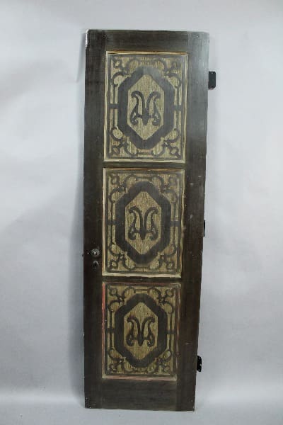 13991. Narrow Spanish Revival 1920's Pantry Door with ornate metal panels featuring symmetrical decorative motifs, positioned upright against a plain background.