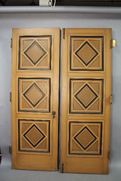 A pair of 14016. Pair Of Fantastic Double Doors From 1920's Spanish House with geometric diamond patterns on each panel, mounted within a grey wall.
