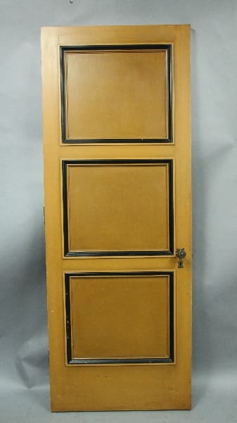 A wooden door with three vertical rectangular panels, featuring a simple knob on the right side, standing against a grey background. 14018. Single Door From Spanish Revival Home