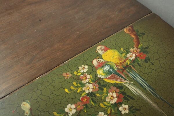 14496. 1920's Hand Painted Bar Cart With Bird Motif with a decorative, painted panel featuring a colorful parrot among floral patterns, showing signs of aging and cracking.