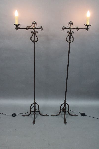 Two 14605. Pair Of 1920's Single Torchieres with lit candles, positioned against a grey backdrop.