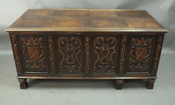 Antique carved walnut desk with great carved front panel and claw feet, set on a grey backdrop.