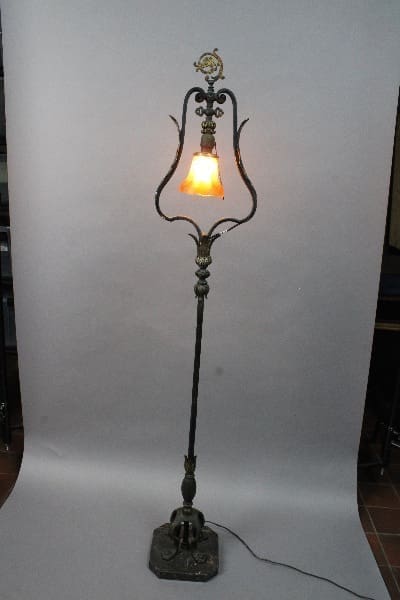 14806. 1920's Floor Lamp In The Manner Of Oscar Bach with ornate metal design and a single lit bulb, positioned against a white backdrop.