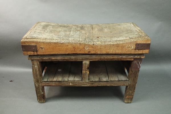 An antique 14825. 19th Century Butcher Block with a worn top and a lower shelf, set against a grey backdrop.
