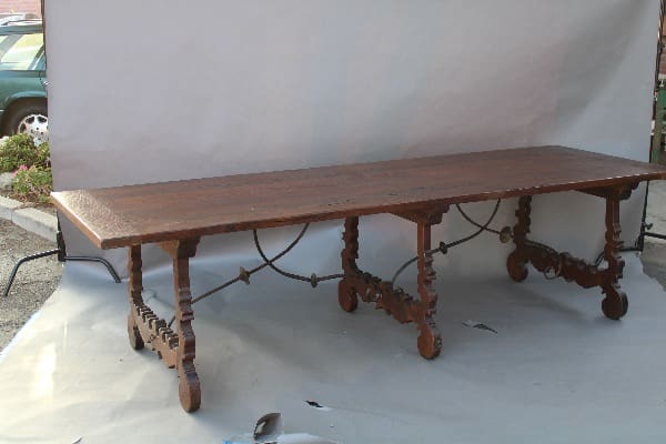 An ornate 14833. Rare Almost 10 Feet Trestle Table With Double Iron Trestles, with intricate leg designs, set against a plain backdrop, outdoors.