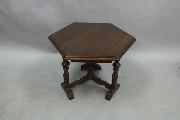 An antique 14843. Spanish Revival Hexagonal Low Walnut Table with ornate legs and casters, positioned against a neutral grey background.
