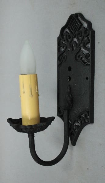 Wall-mounted candle holder with ornate design.