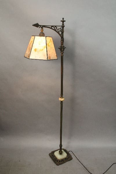 14923. Circa 1920's Bronze And Marble Lamp With New Mica Shade with an ornate metal stand and a stained glass shade, illuminated, against a gray backdrop.