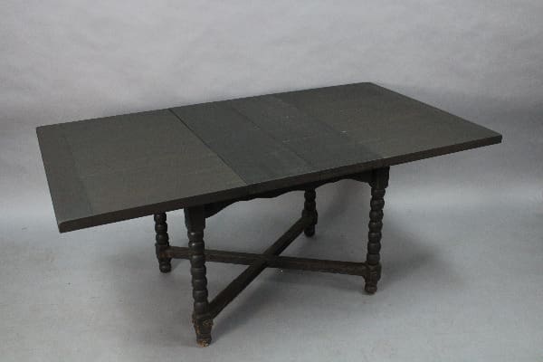 A 14984. Spanish Revival Table With Leafs Circa 1920's with a foldable top and turned legs, displayed against a plain grey background.