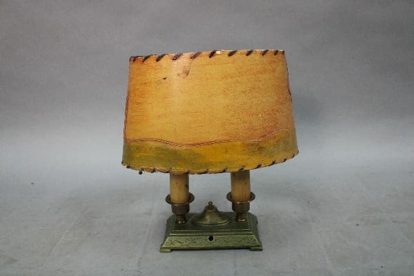 15027. 1920's Table Lamp With Green Base and Original Paper Shade with dual wooden posts, on a decorative brass base, displayed against a grey backdrop.