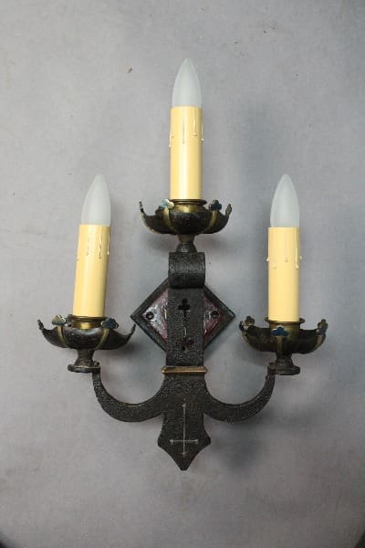Three-candle wall sconce with decorative elements.