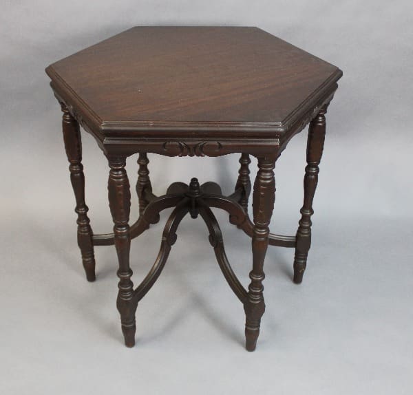 15116. Spanish Revival Walnut Hexagonal Table with carved legs and lower cross braces on a plain grey background.