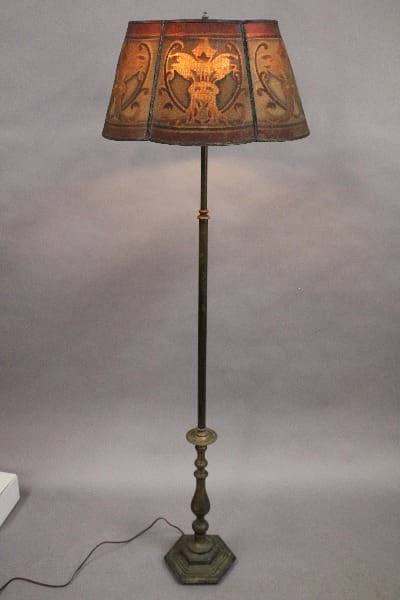 Antique spanish revival lamp with a beautiful screen shade featuring an eagle design, set against a plain gray background.