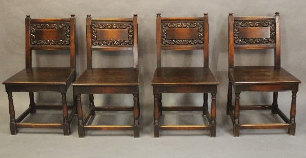 Four antique wooden chairs in a row.