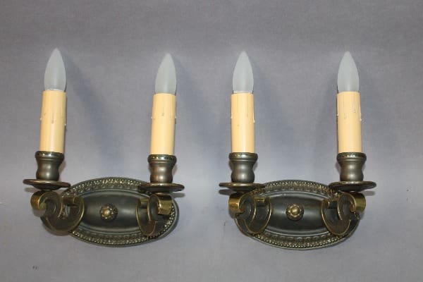 Two vintage wall sconces with candle holders.