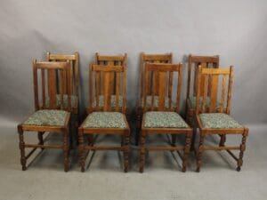 Five 15235. Set Of 8 Arts and Crafts Chairs with floral upholstered seats, aligned in a row against a grey backdrop.