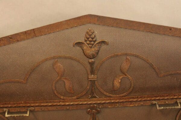 Close-up of an ornate wooden headboard with a mesh inset and a central decorative carving of a 15334. Beautiful Large Scale Peaked Firescreen.