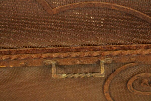 Close-up of a 15334. Beautiful Large Scale Peaked Firescreen with a rusty, metal handle and decorative trim.