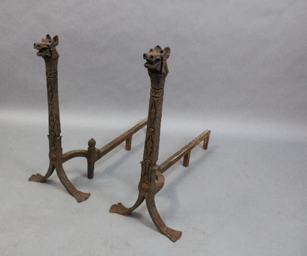 Two carved wooden 15335. Wrought Iron Pair Of Dragon Andirons with giraffe heads at the top, positioned on a light gray background.